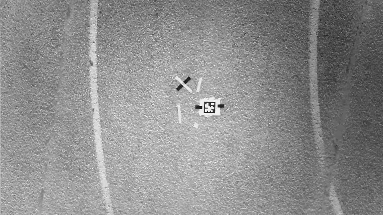 Teach keyframe f01: the downward camera's view of the taped launch mark on asphalt, recorded during the climb.
